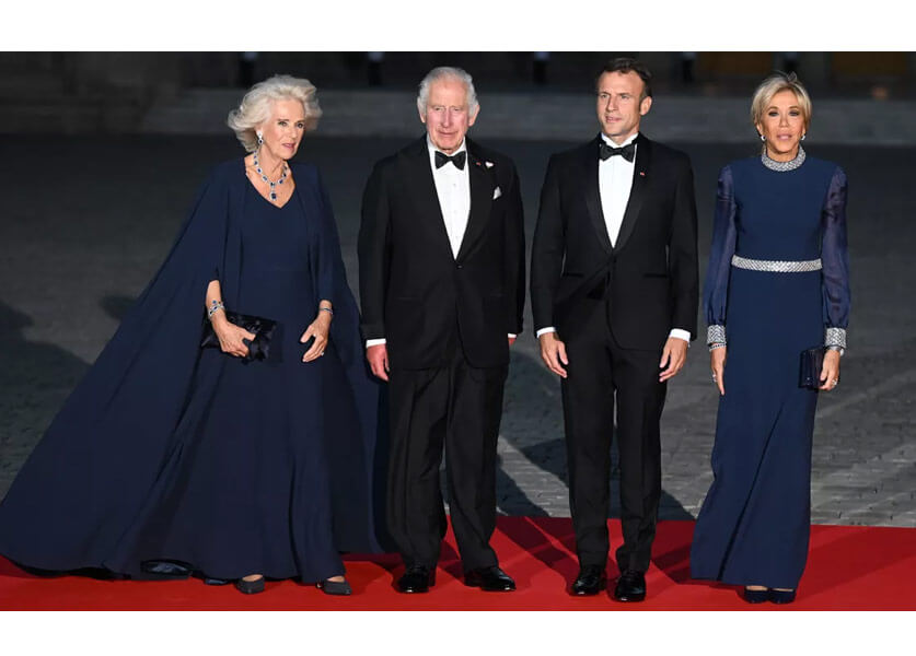 In a midnight blue cape dress, Queen Camilla in perfect harmony with Brigitte Macron at Versailles